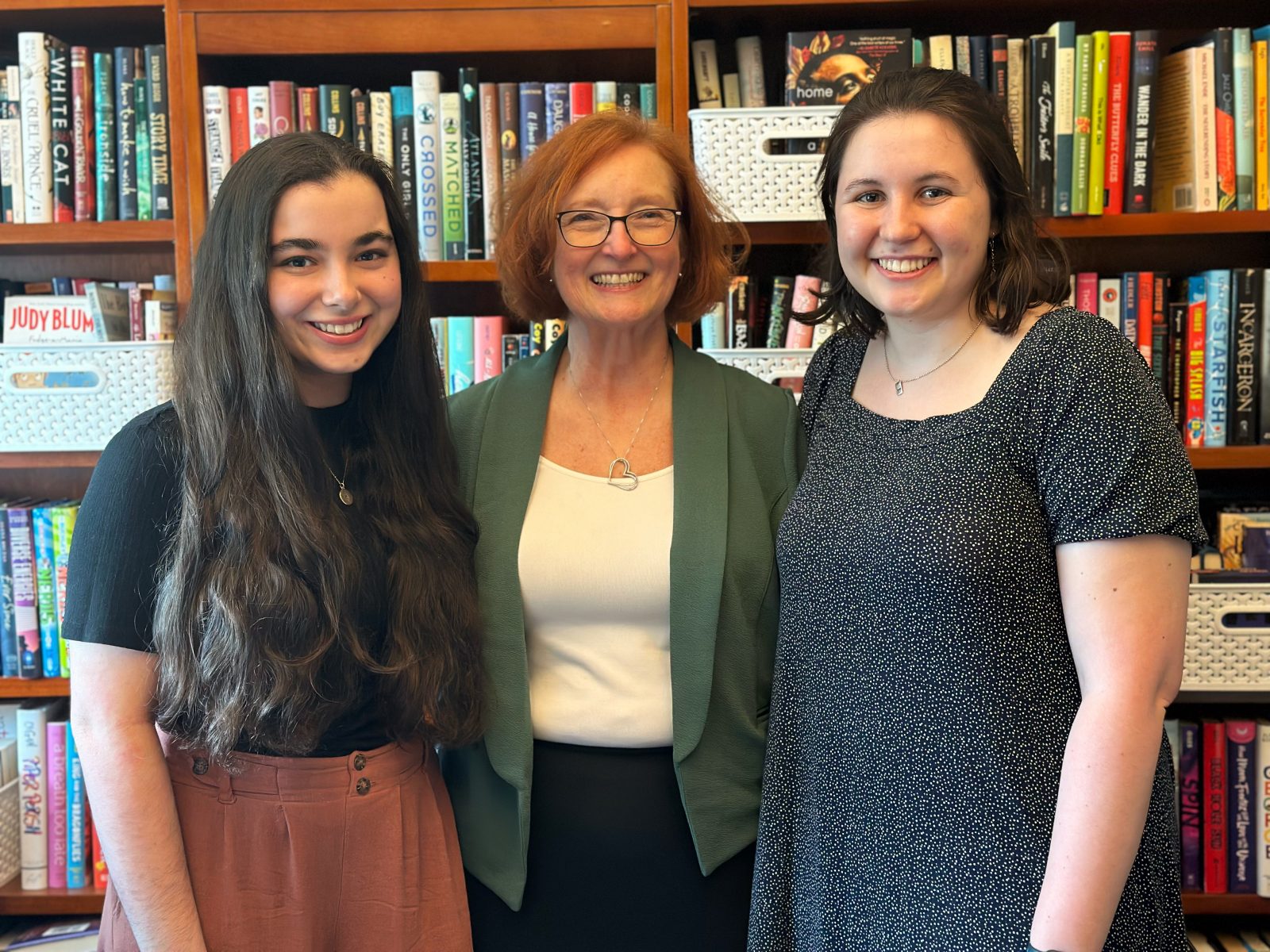 Marissa Tessier, Melanie Hundley and Elizabeth Seeker stand in front of filled bookcases.