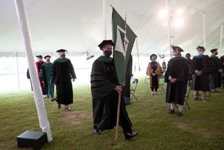 Varun Menon, 2020 class president, carried the school flag as he led the procession to the ceremony. 