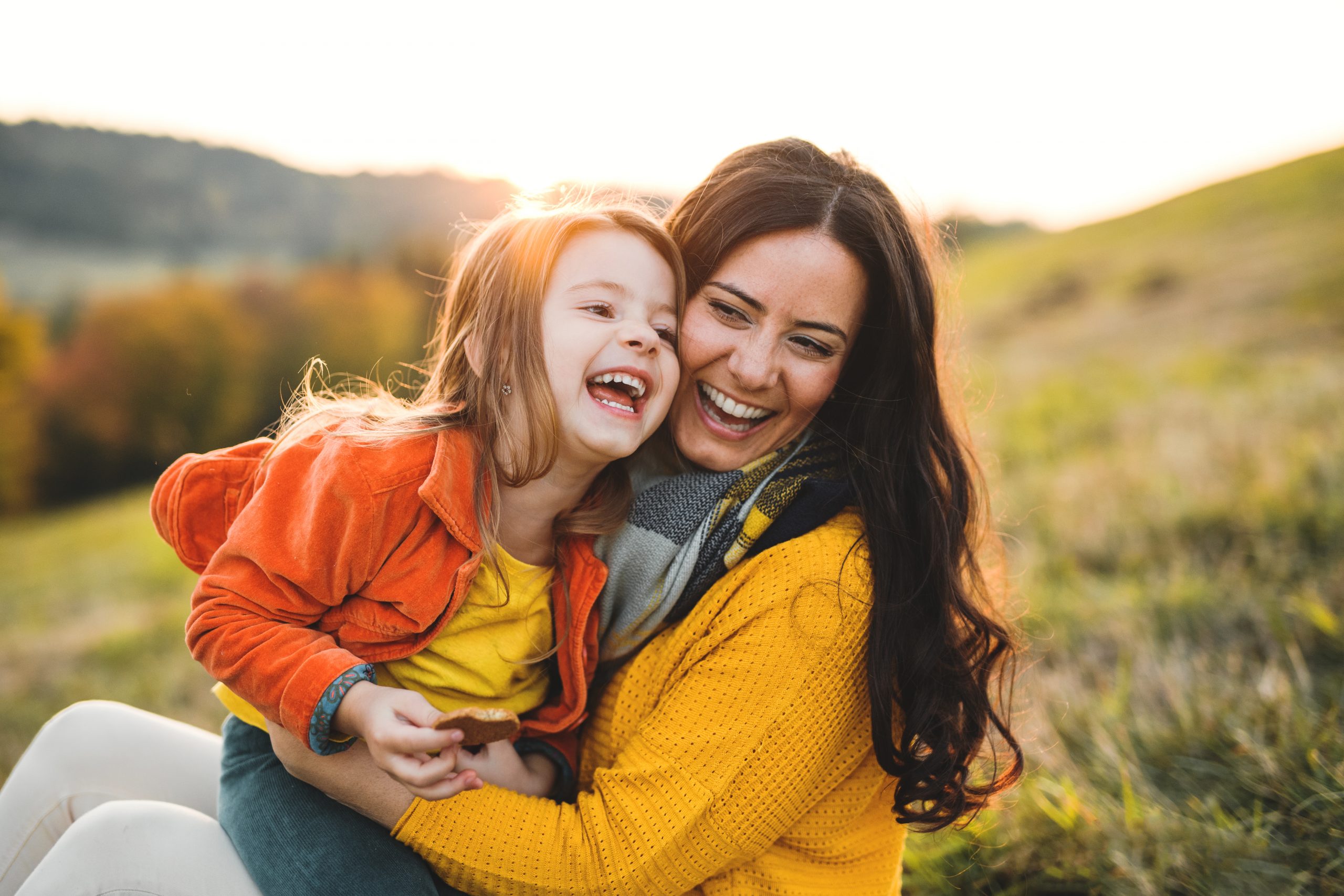 mother and daughter hugging and sitting in the grass