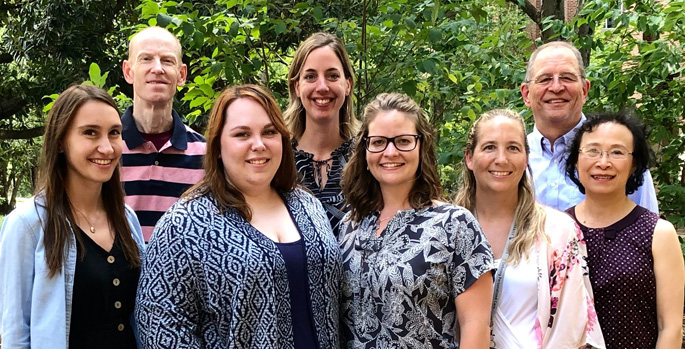Researchers standing outside in front of foliage