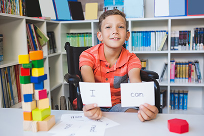 boy holding two flash cards saying I can