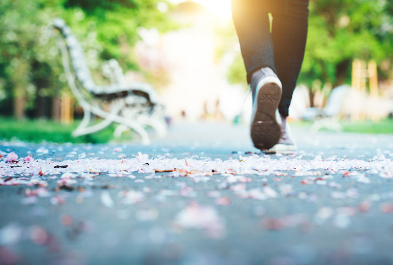 Closeup of a woman's feet in sneakers as she walks a deserted path.