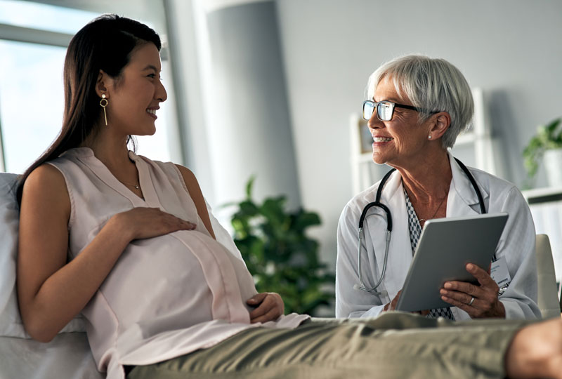 Pregnant Asian woman visits with a maternal-fetal medicine specialist.