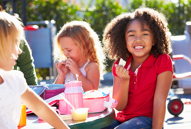 kindergarden children eating lunch outside
