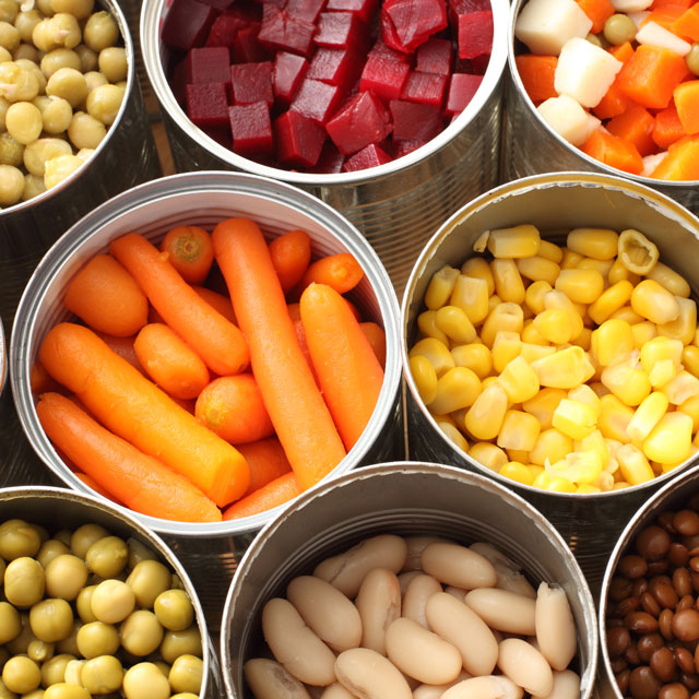 High-angle photo of variety of canned vegetables, with cans open to display the food.