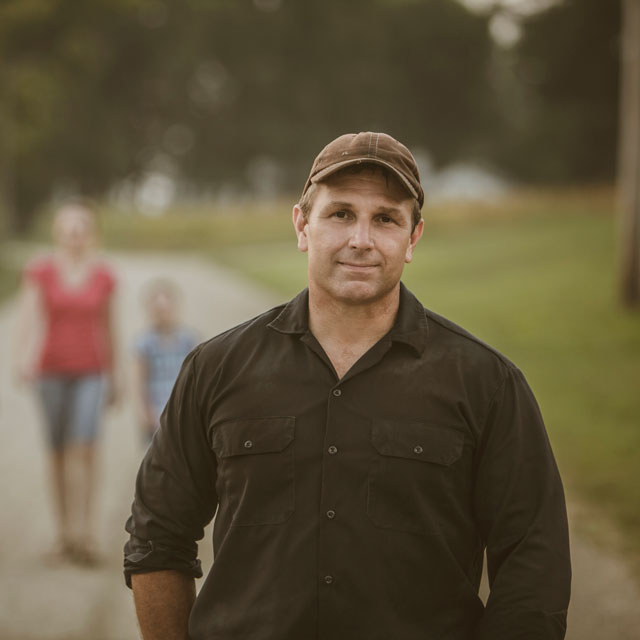 A man walks with his family along a rural path.