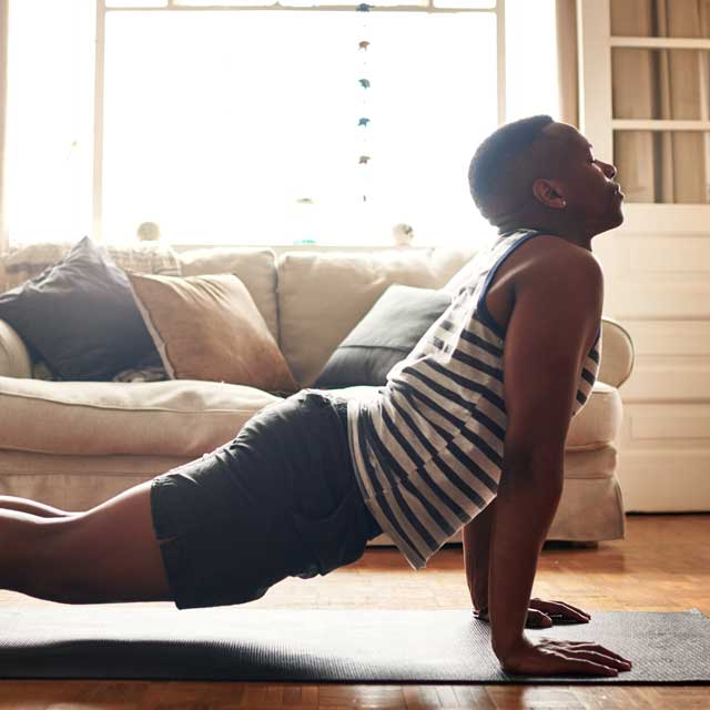 Man doing yoga at home as an exercise to reduce stress.