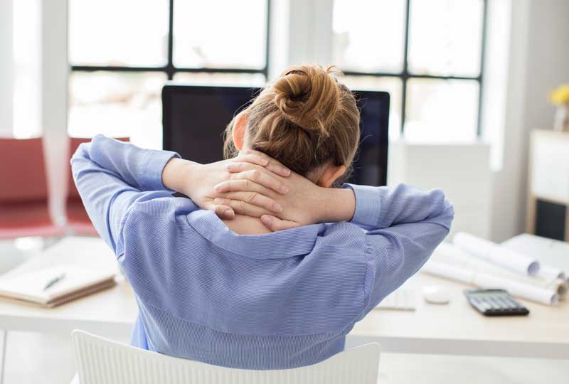 Woman holding the back of her neck to relieve back pain.