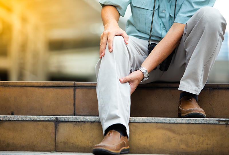 Man experiencing PAD leg pain, holding calf