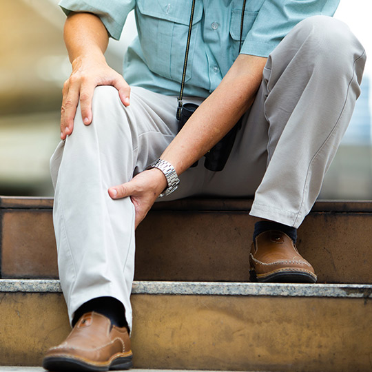 Man experiencing PAD leg pain, holding calf