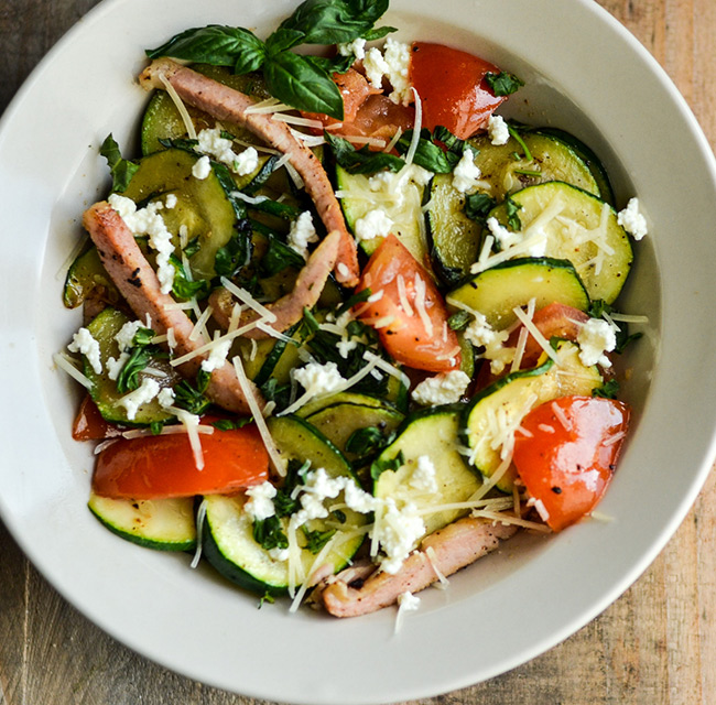 Bowl of zucchini sautéed with tomato and Canadian bacon