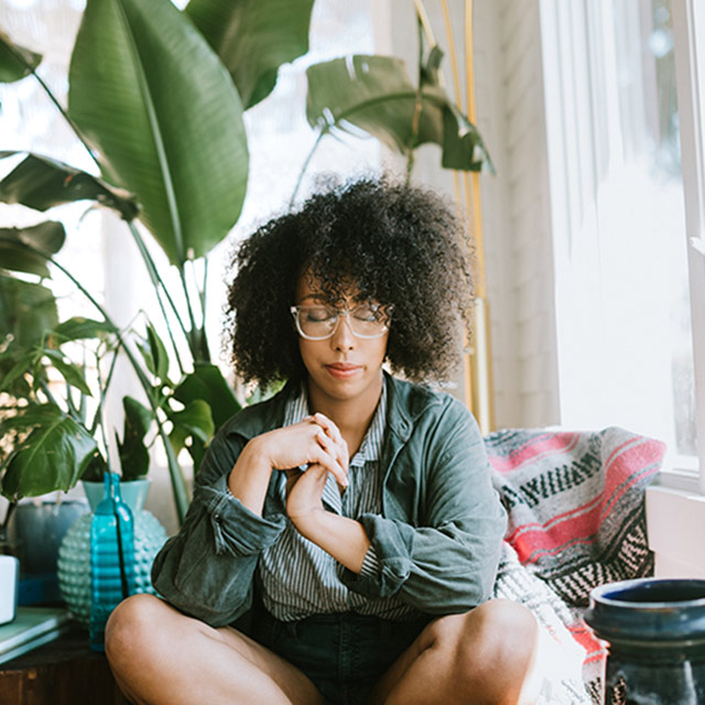 Woman sitting on couch relaxing to help manage stress