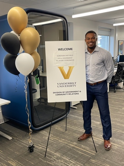 Donovan Sheffield stands next to a welcome sign on his first day with GCR in the Baker Building