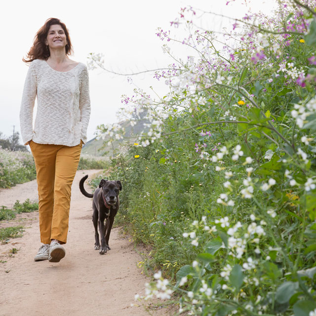Woman walking along a dirt path with two dogs