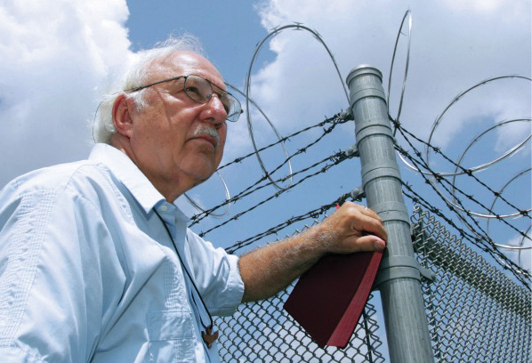 Color portrait of Rev. Don Beisswenger in front of prison fence 