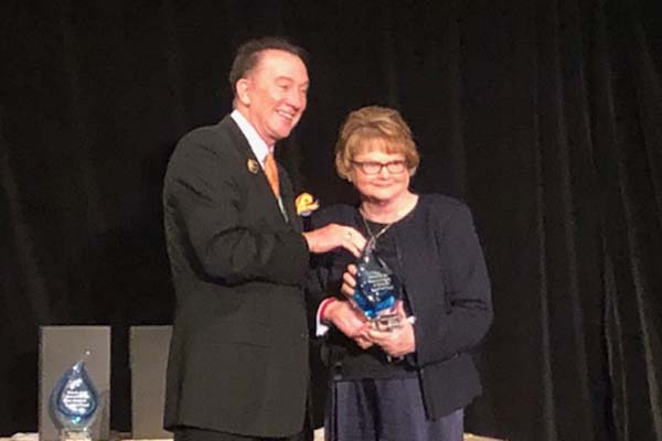 Roy Simpson presents a glass award to Vanderbilt's Besty Werner for Nursing Informatics. Both are dressed formally.