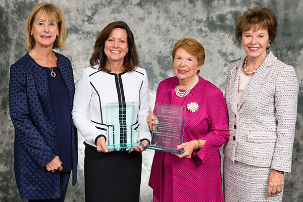 Four women in business attire, with two holding large glass engraved awards. The women are Left, AACN President and CEO Deb Trautman, April Kapu, Linda Norman and AACN Board Chair Ann Cary.