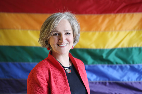 Tonda Hughes in front of rainbow flag