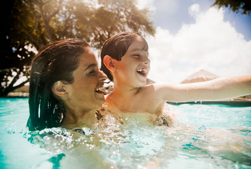 Woman holds a small boy in a swimming pool