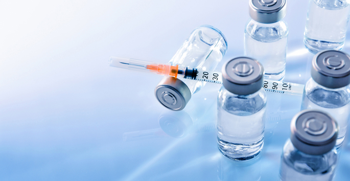 Vials with medication and syringe on blue methacrylate table. Horizontal composition. Top elevated view.