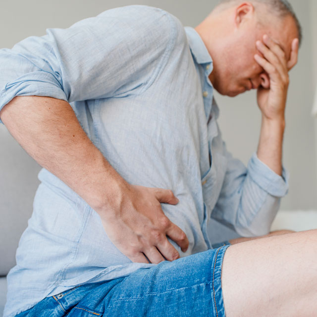Man suffering from fatty liver disease and clutching stomach.