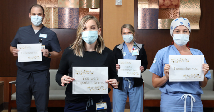The Rev. Ian Cullen, MDiv, left, Samantha Osborne, PA, Jessica Bowman Williams, RN, CCRN, and Casey Lary, RN, hold signs remembering and honoring patients who have died. VUMC employees will hold similar signs during part of a special virtual event called “VUMC Remembers” on Nov. 22.