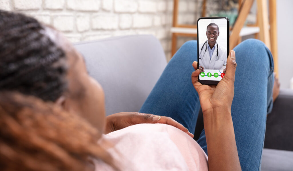 Pregnant woman talking to doctor through virtual call on phone