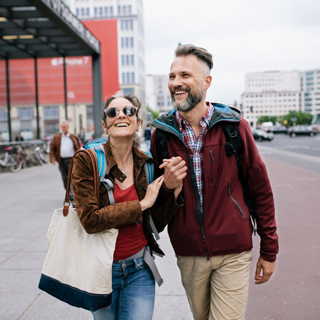 A middle-aged couple walk arm-in-arm along a city street.