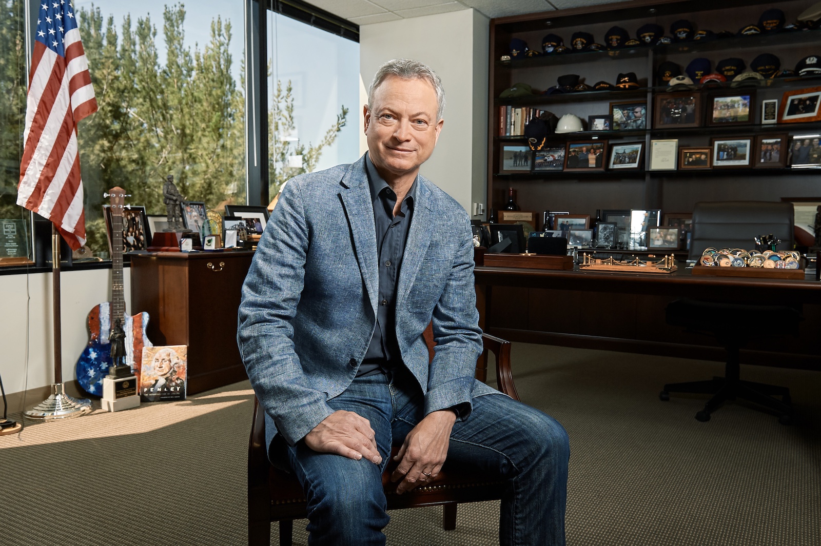 Gary Sinise sits in a chair in his office.