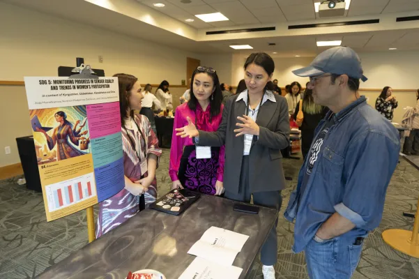 Poster presentation: Women’s empowerment and progress in Uzbekistan, Kazakhstan, Kyrgyzstan, and China: (left to right): Nurkhon Madyarova, Chinara Abdymomunova, and Aida Mametkanova presenting to attendee, 11/15/24 (Photo by Joe Howell/Vanderbilt University)