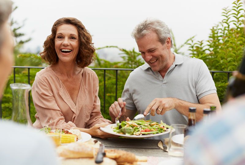 A middle-aged white couple eat a light meal outdoors.