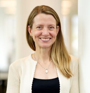 A woman in a white sweater and black shirt smiles