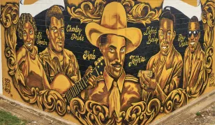 A gold, brown and black mural of five trailblazing Black country music stars spans two corners of Vanderbilt Printing Services on Chestnut Street in Nashville.