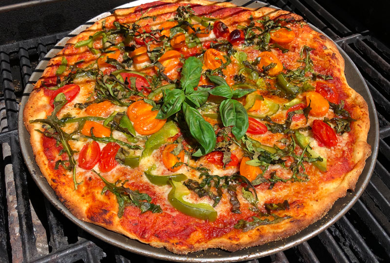 Grilled pizza topped with fresh vegetables and herbs.