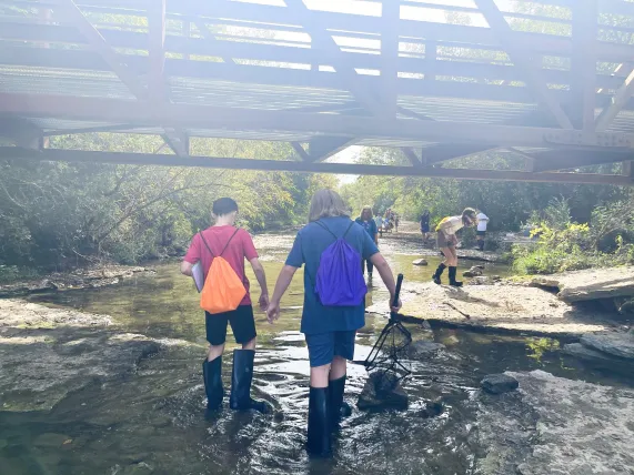 Middle school students walk through Mill Creek.