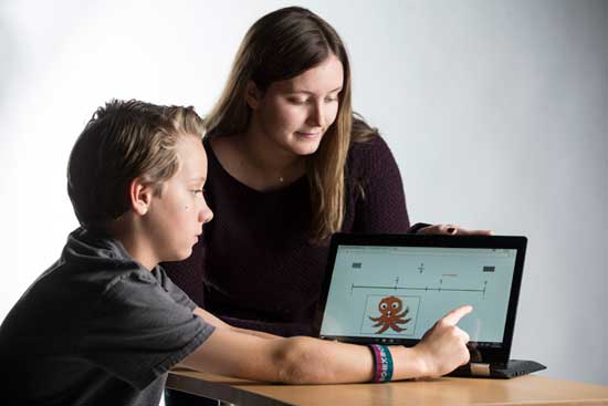 Lisa Fazio's research assistant Emily Nordberg (a senior) instructs a fifth-grader on how to play the fractions learning game. (Joe Howell/Vanderbilt)