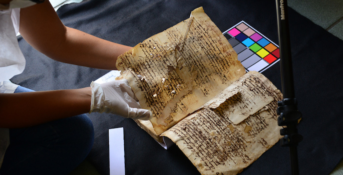 fragile, falling apart old book being positioned for scanning by gloved hands