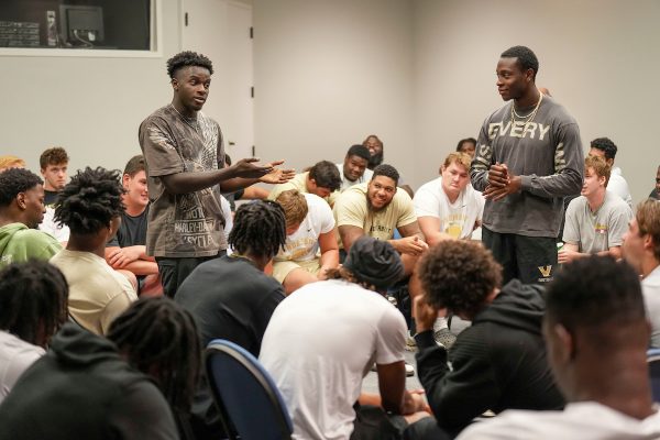Students stand in the middle of a group speaking to each other