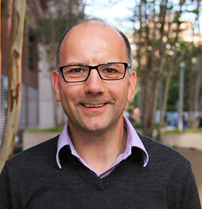 Photo of Neuert standing in the plaza in front of Light Hall on campus.