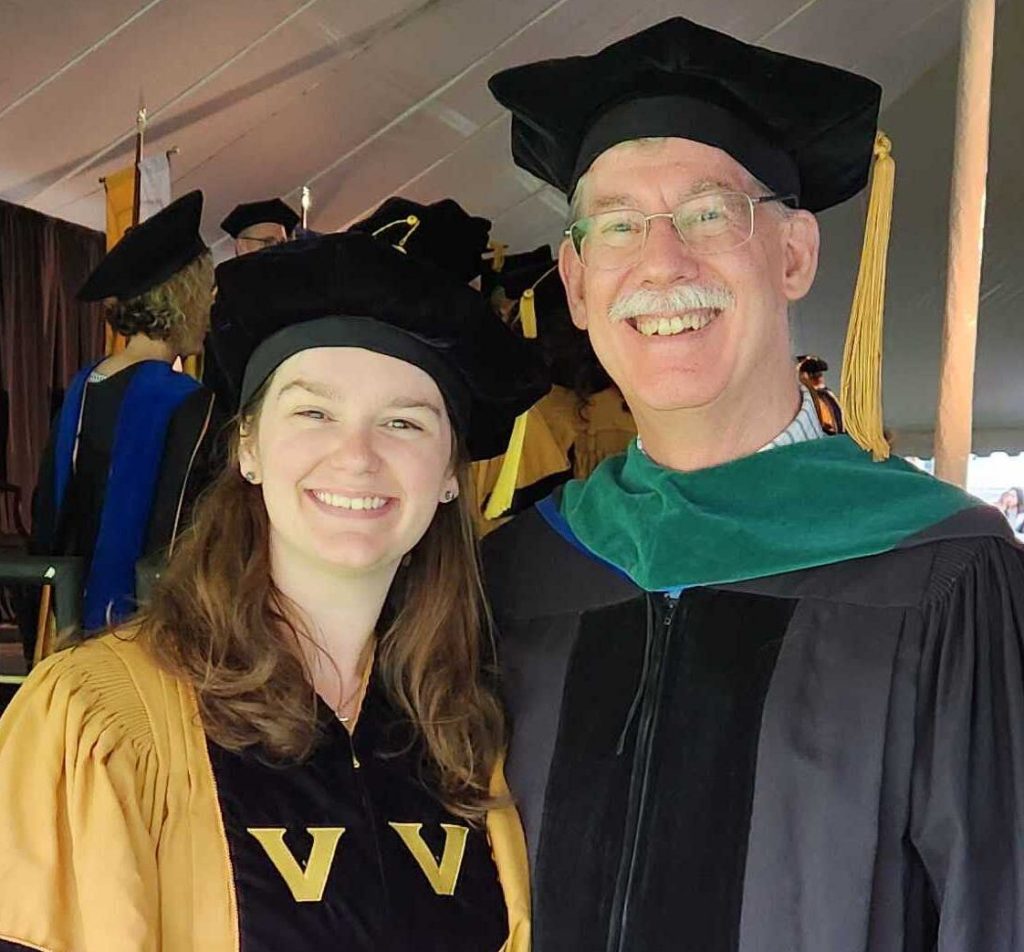 Cover and Shuman in doctoral graduation regalia. Shuman is in black and gold and Cover is in black and green.