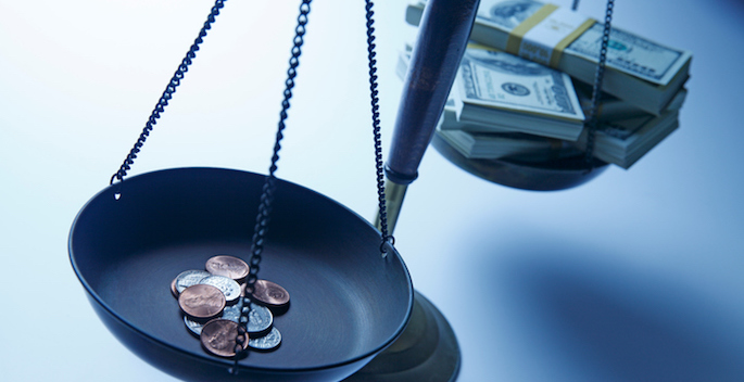 A stack of cash and a stack of pennies on a scale.