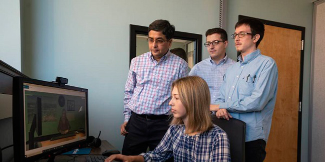 Left, Nilanjan Sarkar, professor of mechanical engineering, is the lead investigator on a significant new NSF convergence grant. He, Joshua Wade, a senior staff research scientist, Michael Breen, an intern on the project, and Claire Barnett, communications coordinator at the Frist Center for Autism and Innovation, work an interactive prototype, developed with Microsoft support, that prepares applicants with ASD for job interviews. (Vanderbilt/Joe Howell)