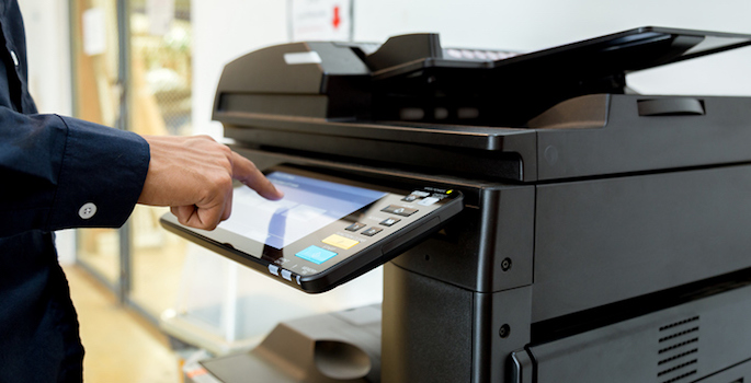 close-up of man's hand on the control panel of a copy machine