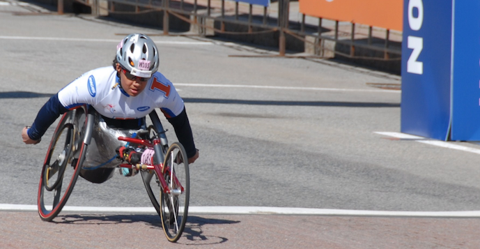 Anjali in wheelchair crossing finish line at marathon