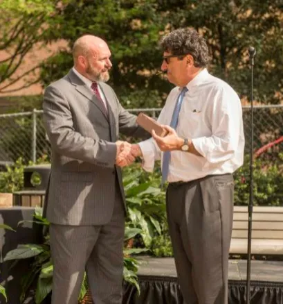 Chancellor Nicholas S. Zeppos accepts a commemorative brick from the power plant from Assistant Vice Chancellor Mark Petty at an April 9 event celebrating the end of coal on campus and the demolition of the university's iconic smokestack.