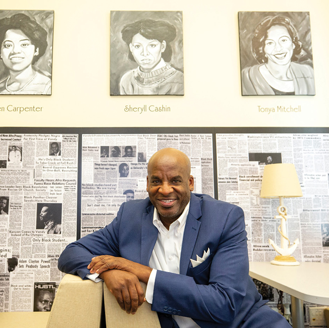 Artist James Threalkill sitting beneath his paintings at the Black Cultural Center