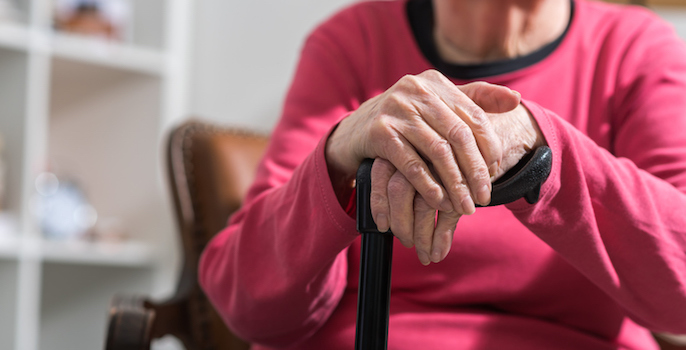Elderly caucasian woman with her hands on a cane