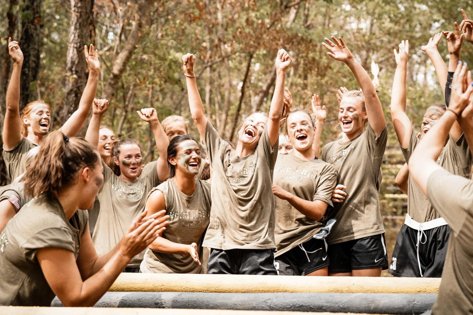 Members of the lacrosse team laugh and cheer while completing challenges at Fort Campbell.