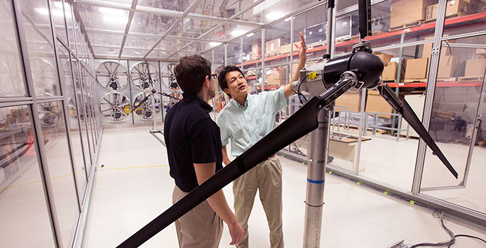 Two people examine a turbine inside the wind tunnel
