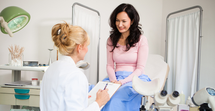 woman and female gynecologist talking in exam room